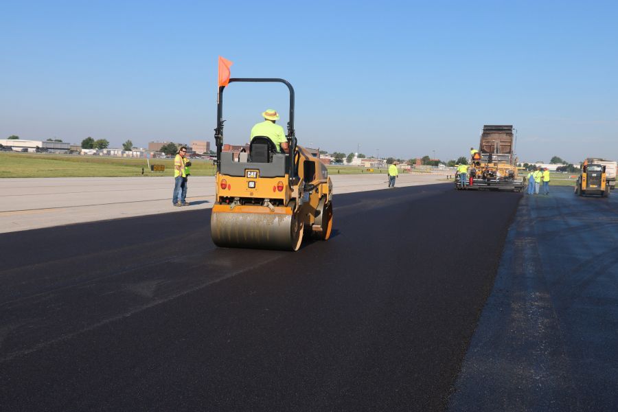 asphalt contractor driving an asphalt roller to help smooth out the asphalt paving